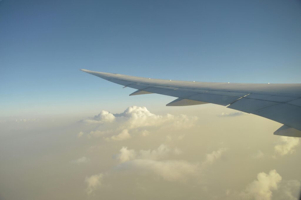 Serene view from an airplane window showing clouds and a wing over Vancouver during daylight.