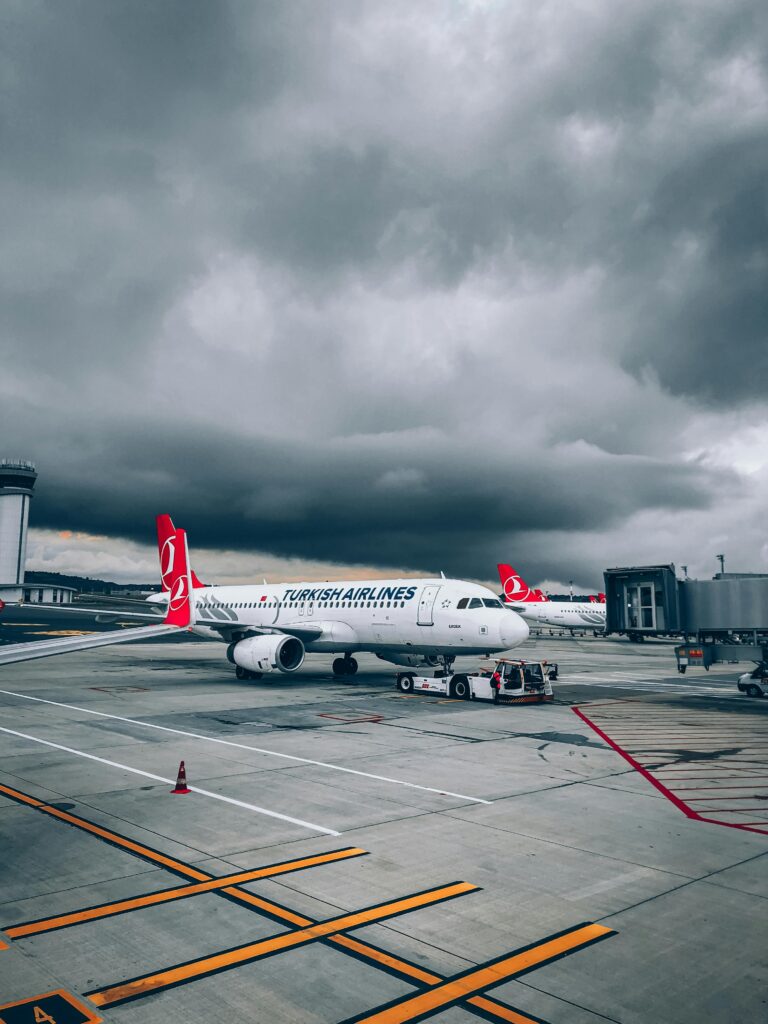 A Turkish Airlines aircraft parked on a runway under a dramatic cloudy sky.