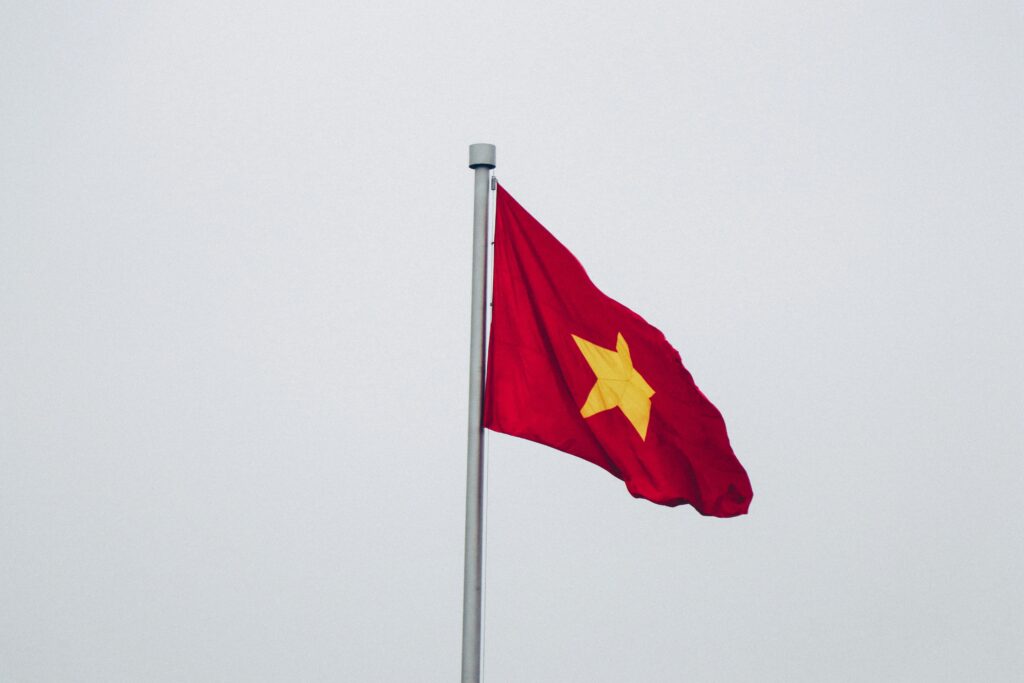 A vivid capture of the Vietnamese flag waving against a clear, overcast sky, symbolizing patriotism and freedom.