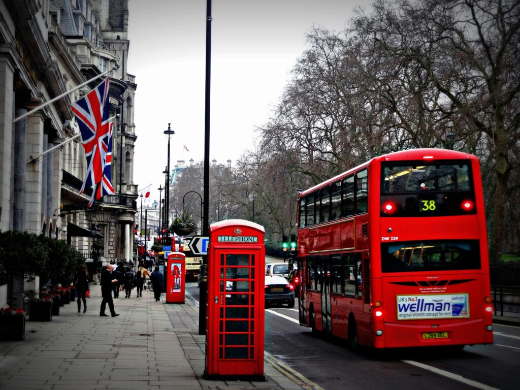 Classic London scene featuring a red double-decker bus and iconic phone booth on a busy city street.