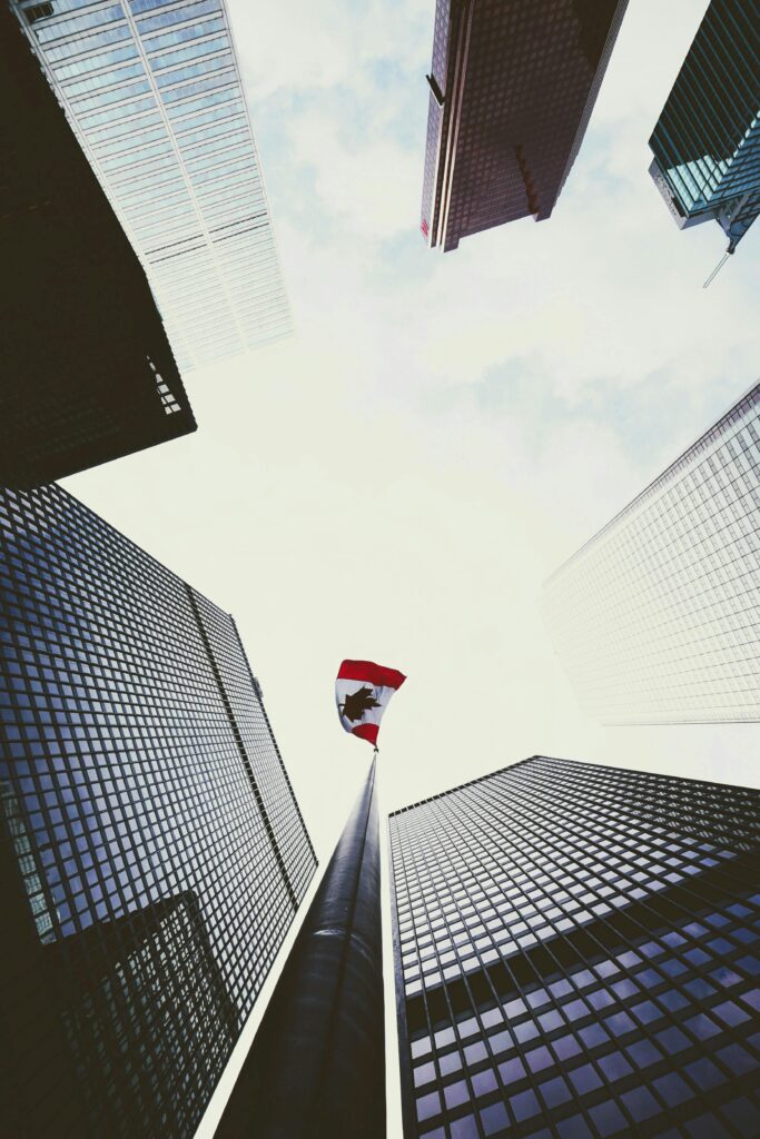 Dramatic low angle view of skyscrapers surrounding a Canadian flag in downtown Toronto.