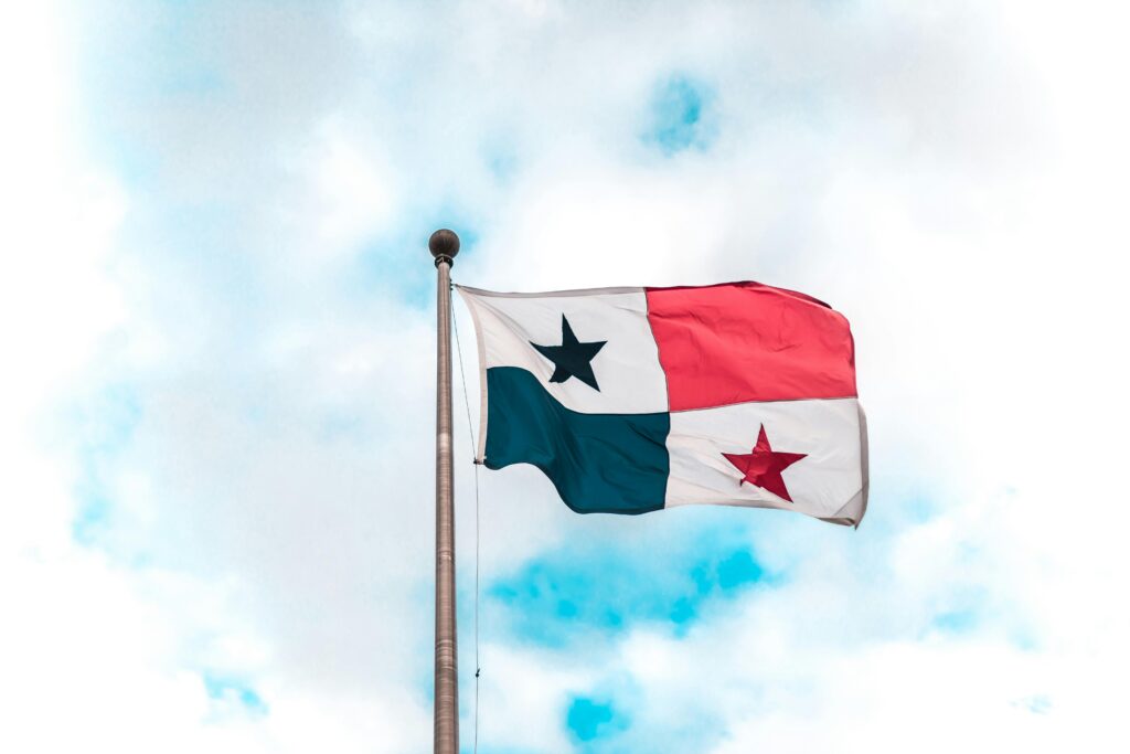Panama national flag waving on a flagpole against a bright blue sky.
