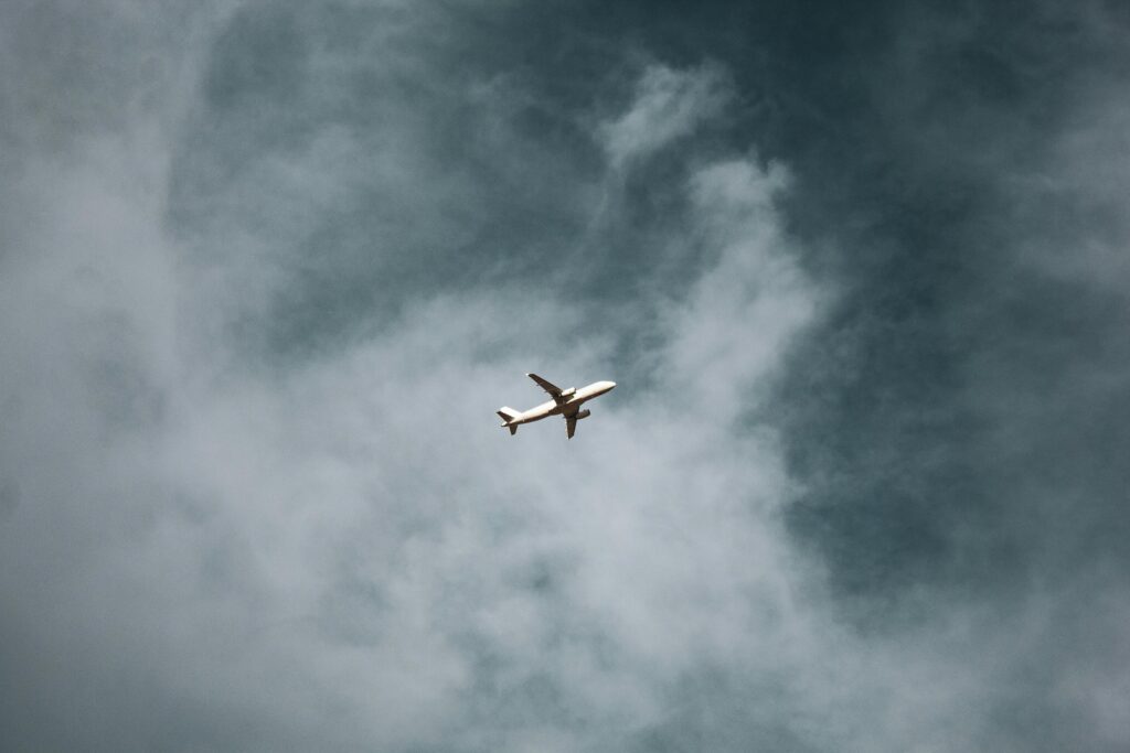 A commercial airplane soaring through vast clouds in the sky, capturing a sense of travel and exploration.