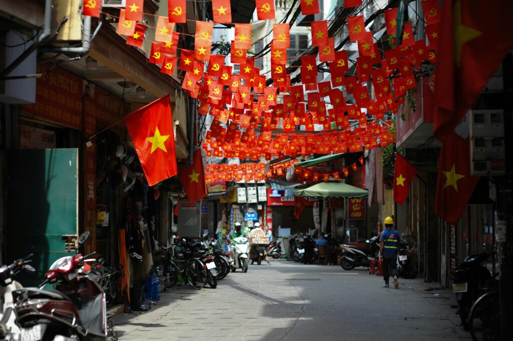 A lively street in Hanoi adorned with numerous Vietnamese flags, capturing local culture.