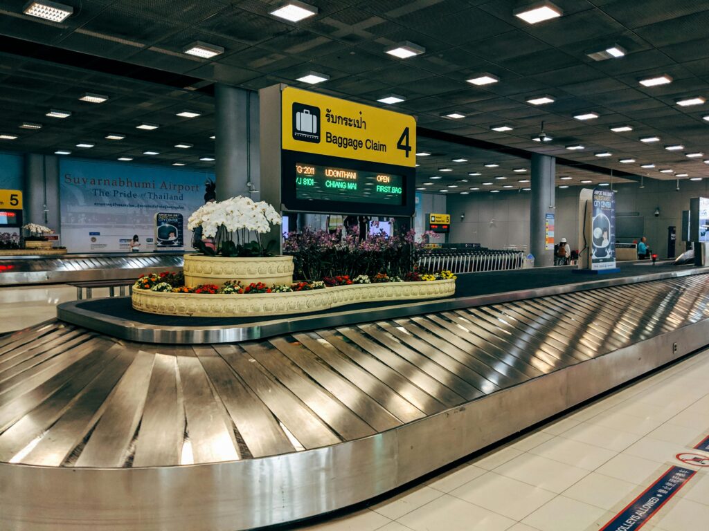 Modern baggage claim area at Suvarnabhumi Airport in Bangkok with luggage carousel and signage.