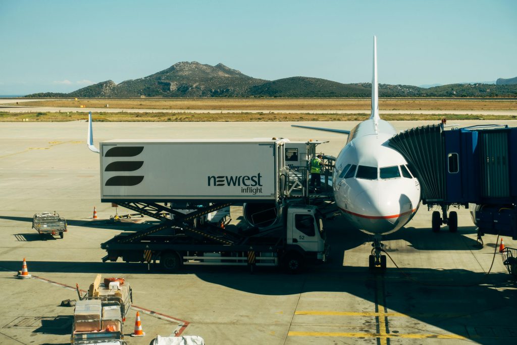 A commercial airplane being serviced at an airport with fueling and loading equipment.