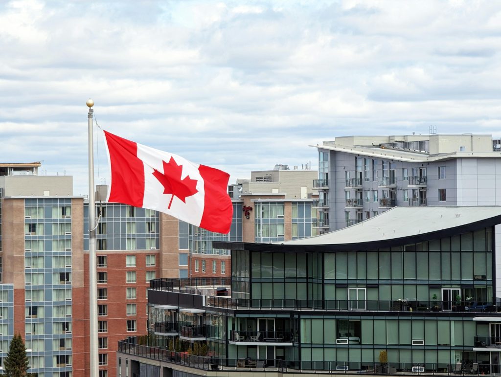 Canadian flag waving prominently in Halifax skyline with modern architecture.