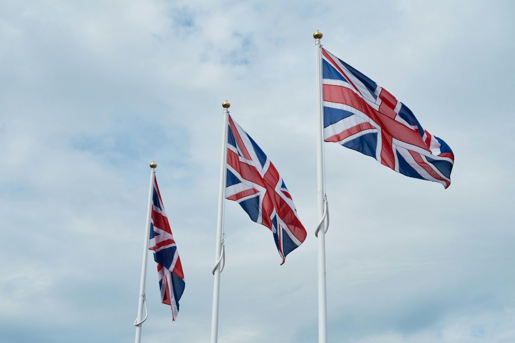 Three Union Jack flags waving against a cloudy sky in Penrith, England.