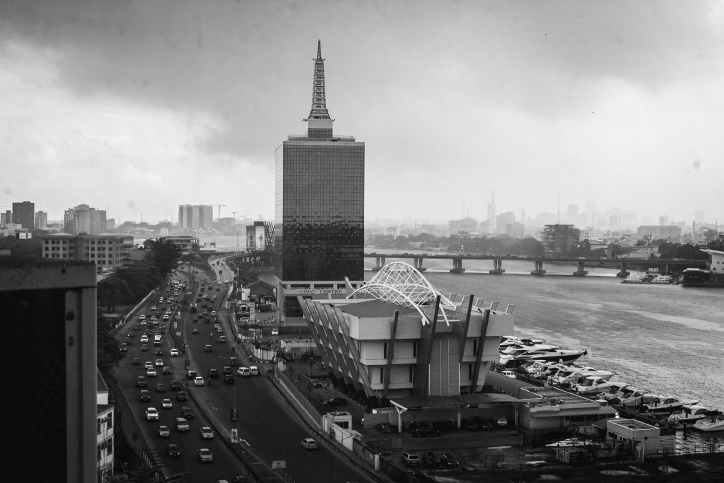 Black and white cityscape of Lagos with a prominent architectural structure and busy road.