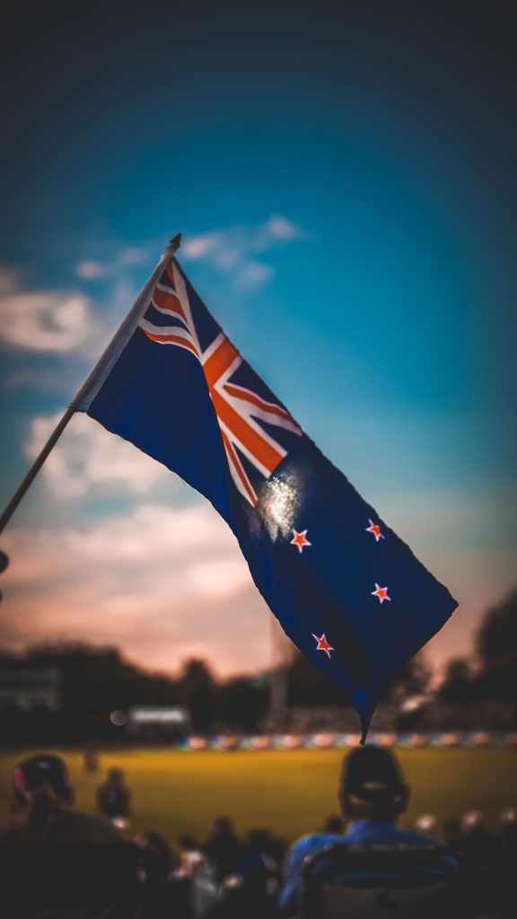 Vibrant New Zealand flag waving with a colorful sky backdrop, capturing patriotism.