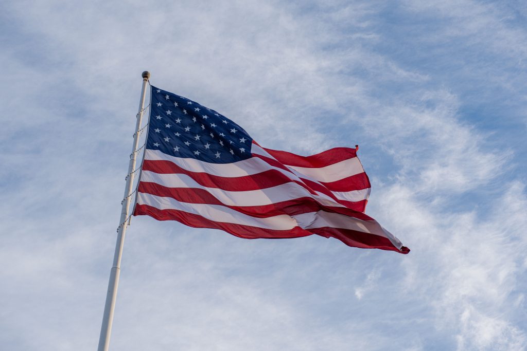 The American flag waves proudly against a backdrop of blue sky, symbolizing freedom and patriotism.
