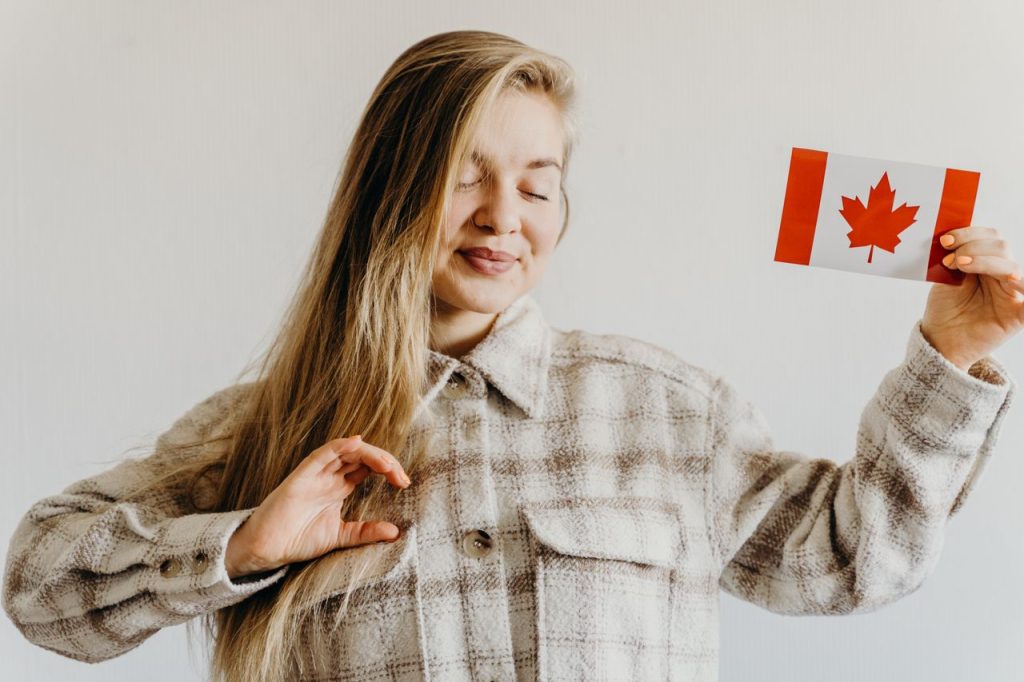 Blonde woman with closed eyes holding Canada flag symbolizing pride and celebration.